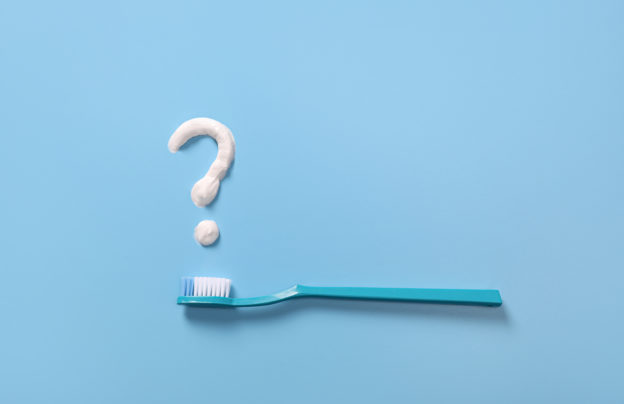 Plastic toothbrushes with toothpaste question mark