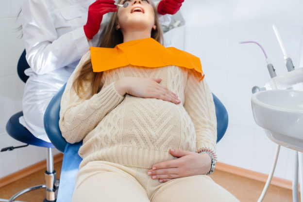 A professional dentist treats and examines the oral cavity of a pregnant girl in a modern dental office. Dentistry.